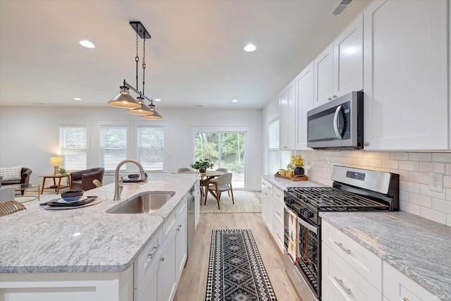 kitchen with a center island with sink, sink, appliances with stainless steel finishes, and white cabinetry