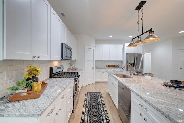 kitchen with white cabinetry, decorative light fixtures, and stainless steel appliances