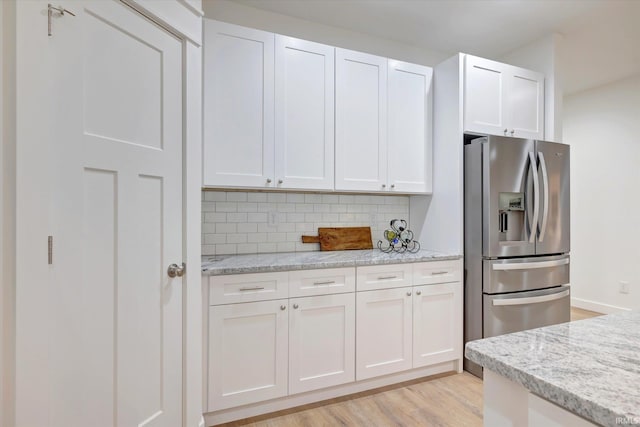 kitchen featuring white cabinetry, light hardwood / wood-style flooring, stainless steel refrigerator with ice dispenser, and decorative backsplash