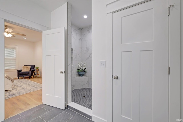 bathroom with ceiling fan, tiled shower, and hardwood / wood-style floors