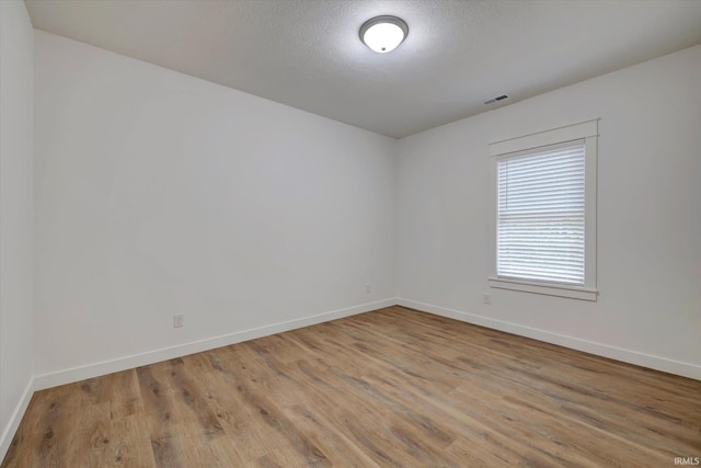 unfurnished room with a textured ceiling and light wood-type flooring