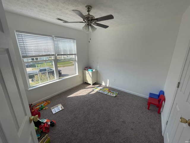 recreation room with carpet, a textured ceiling, and ceiling fan