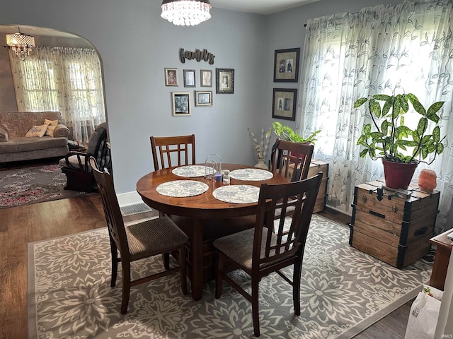 dining area with wood-type flooring and an inviting chandelier