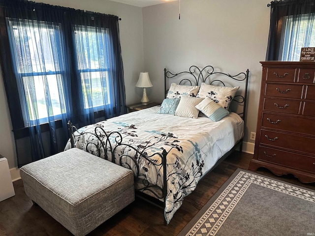 bedroom with multiple windows and dark wood-type flooring