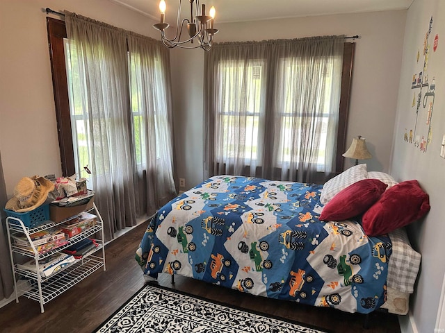 bedroom with a notable chandelier and dark wood-type flooring