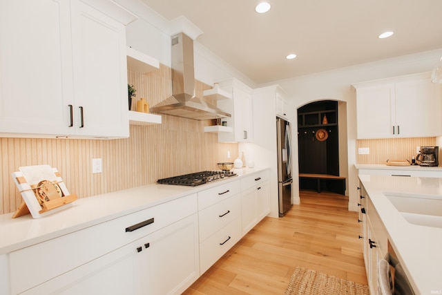 kitchen with sink, light wood-type flooring, white cabinetry, stainless steel appliances, and extractor fan