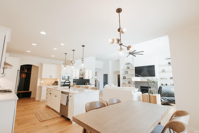 dining room with sink, ceiling fan, built in features, and light hardwood / wood-style flooring