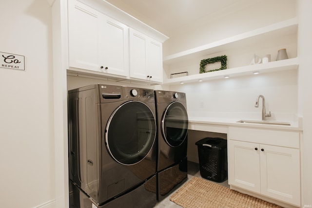 washroom with cabinets, independent washer and dryer, and sink