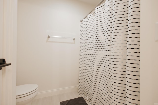 bathroom with toilet, hardwood / wood-style flooring, and curtained shower