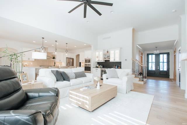 living room with crown molding, french doors, light hardwood / wood-style floors, and ceiling fan