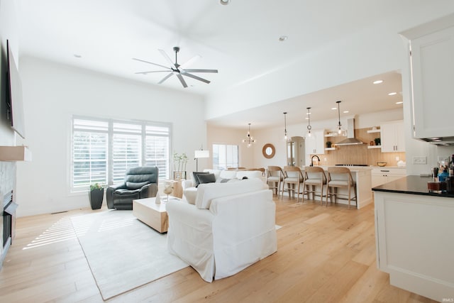 living room with light hardwood / wood-style floors and ceiling fan with notable chandelier