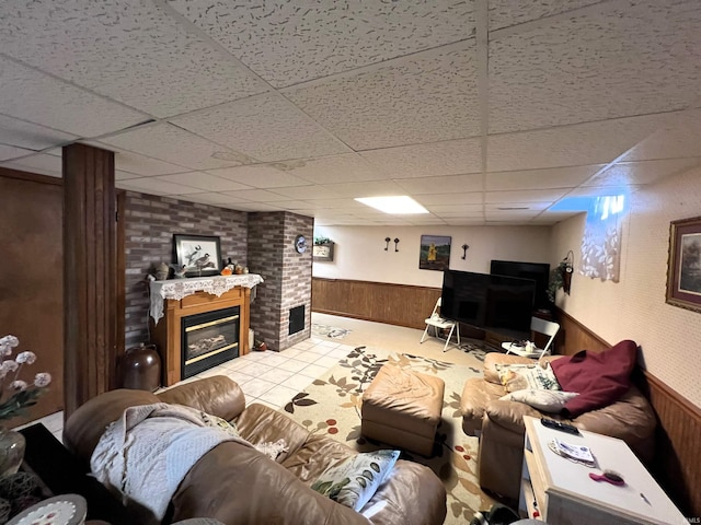 living room featuring tile patterned flooring, a paneled ceiling, and wood walls