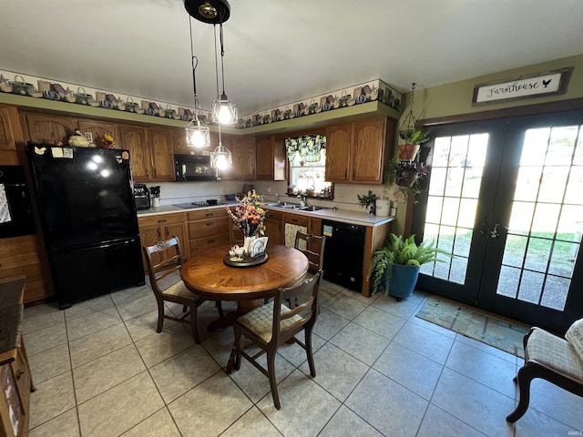 kitchen with sink, hanging light fixtures, light tile patterned floors, black appliances, and french doors