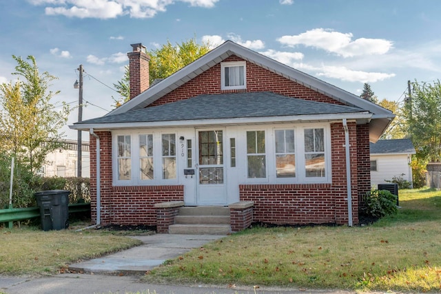 bungalow featuring a front lawn and central AC unit