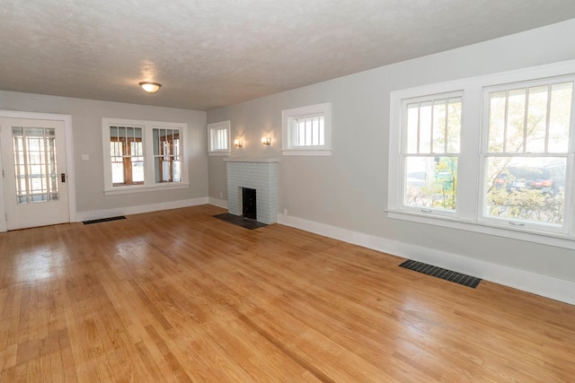 unfurnished living room with light hardwood / wood-style flooring, a textured ceiling, and a fireplace