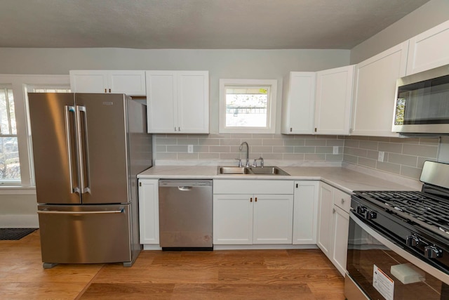 kitchen featuring sink, appliances with stainless steel finishes, light wood-type flooring, and white cabinetry