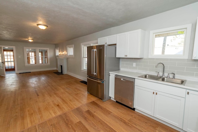 kitchen featuring appliances with stainless steel finishes, a brick fireplace, sink, and light hardwood / wood-style floors