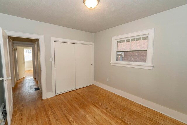 unfurnished bedroom featuring a closet, a textured ceiling, and light wood-type flooring