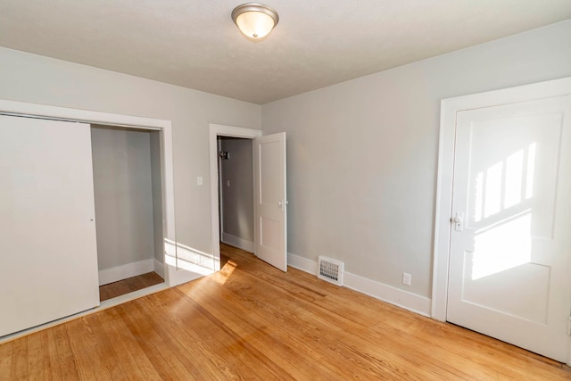 unfurnished bedroom featuring light hardwood / wood-style flooring and a closet