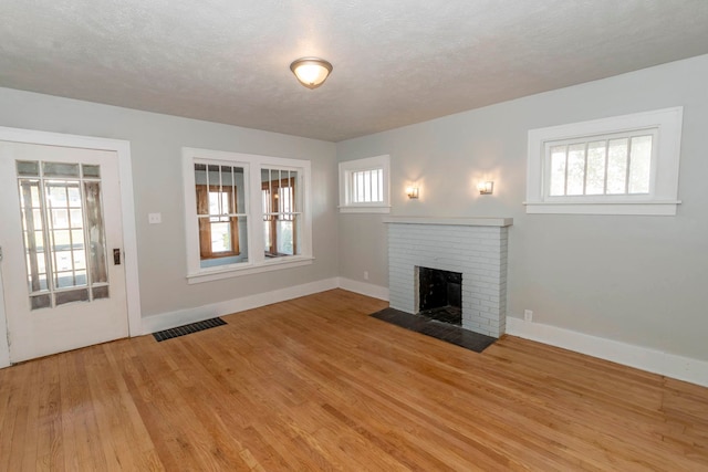 unfurnished living room with a healthy amount of sunlight, a textured ceiling, and light wood-type flooring