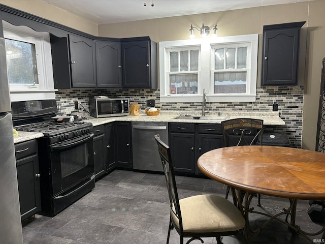 kitchen featuring appliances with stainless steel finishes, tasteful backsplash, light stone counters, and sink