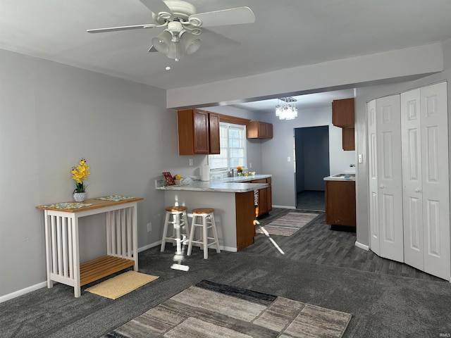 kitchen featuring ceiling fan, dark carpet, a kitchen bar, and kitchen peninsula