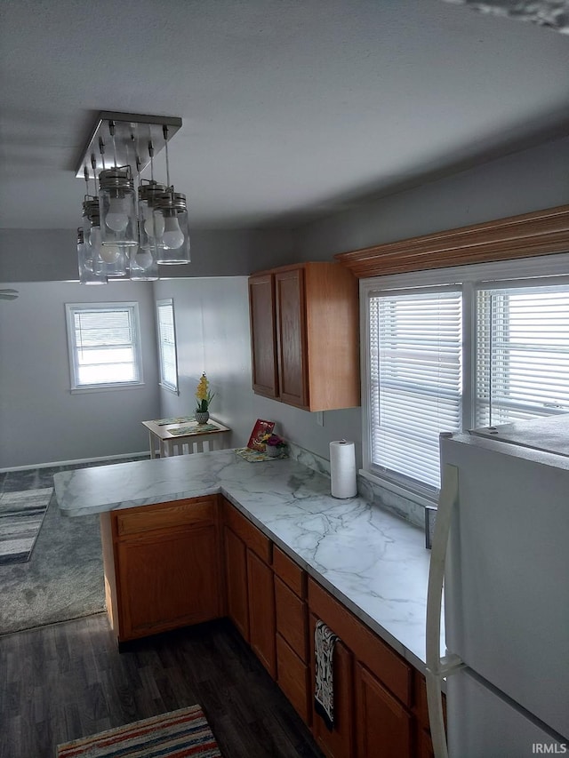 kitchen with dark wood-type flooring, white refrigerator, and kitchen peninsula