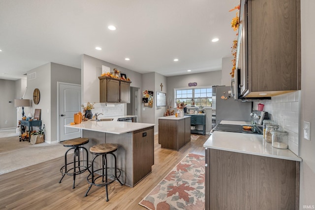 kitchen featuring appliances with stainless steel finishes, tasteful backsplash, a center island, and light wood-type flooring