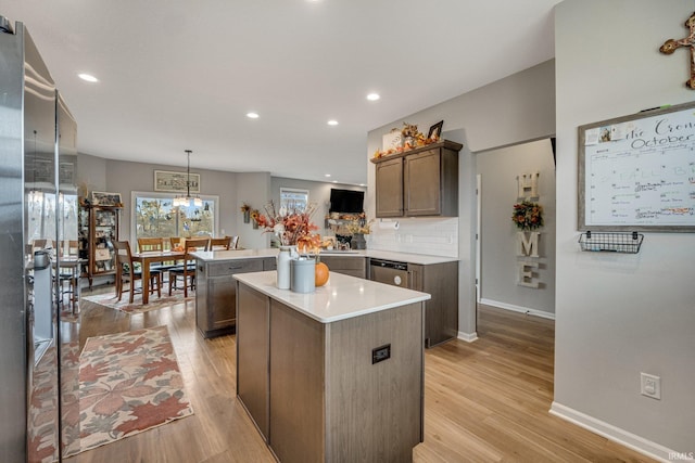 kitchen featuring stainless steel dishwasher, a center island, hanging light fixtures, and light hardwood / wood-style floors