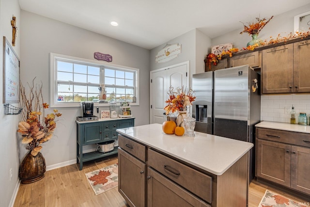 kitchen featuring backsplash, stainless steel fridge, light hardwood / wood-style flooring, and a kitchen island