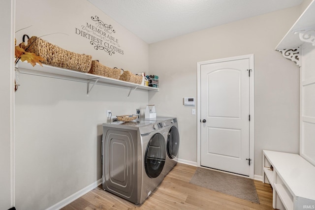 laundry room featuring light hardwood / wood-style flooring, independent washer and dryer, and a textured ceiling