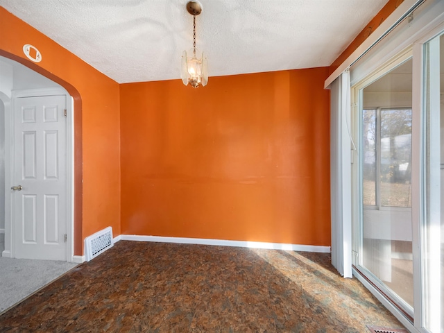 spare room featuring a notable chandelier and a textured ceiling