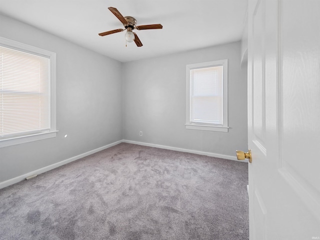 carpeted spare room featuring a healthy amount of sunlight and ceiling fan