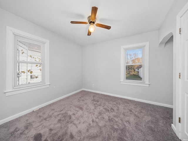 carpeted empty room with ceiling fan and plenty of natural light