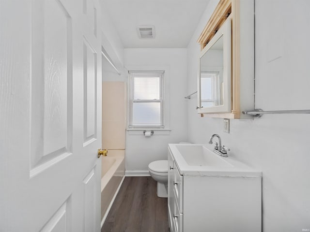 bathroom featuring toilet, a tub, hardwood / wood-style flooring, and vanity