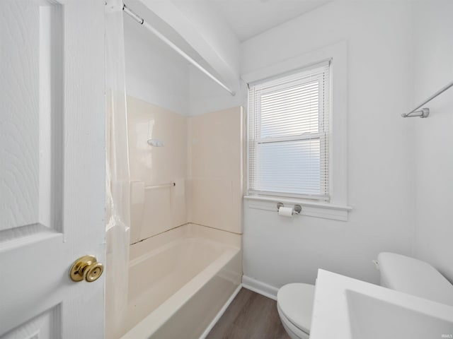 bathroom featuring toilet, hardwood / wood-style flooring, and bathing tub / shower combination