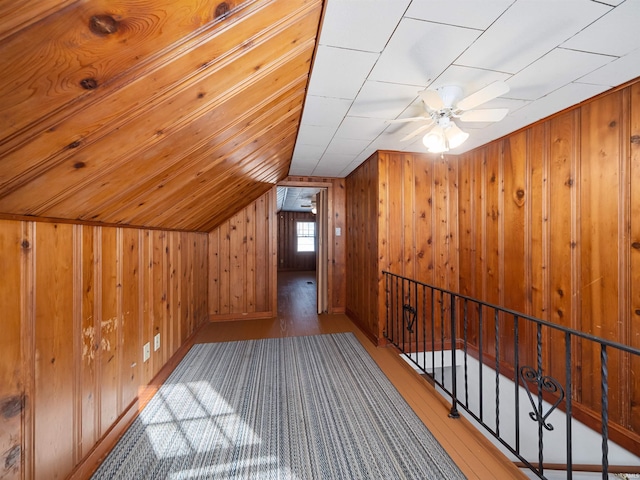 additional living space with wooden walls, vaulted ceiling, wood-type flooring, and ceiling fan