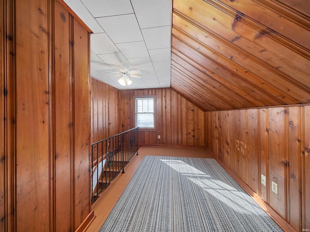 bonus room with wooden walls, vaulted ceiling, and ceiling fan