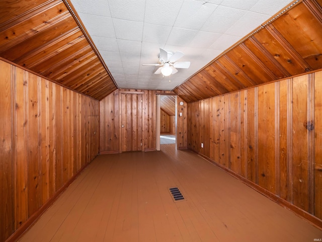 additional living space featuring light hardwood / wood-style floors, wood walls, lofted ceiling, and ceiling fan