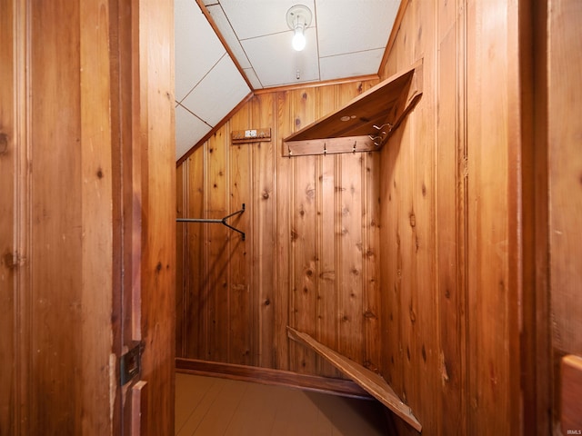 mudroom featuring lofted ceiling and wood walls