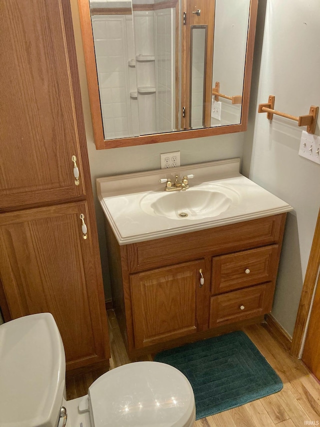 bathroom with toilet, hardwood / wood-style floors, and vanity