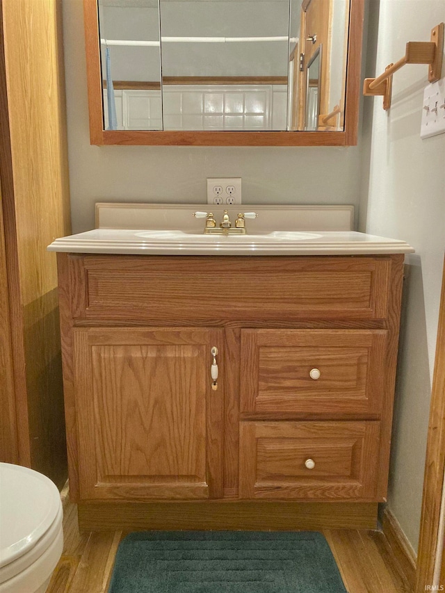 bathroom with vanity, toilet, and hardwood / wood-style flooring