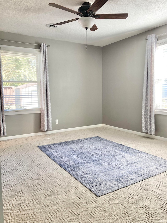 carpeted spare room featuring a textured ceiling and ceiling fan