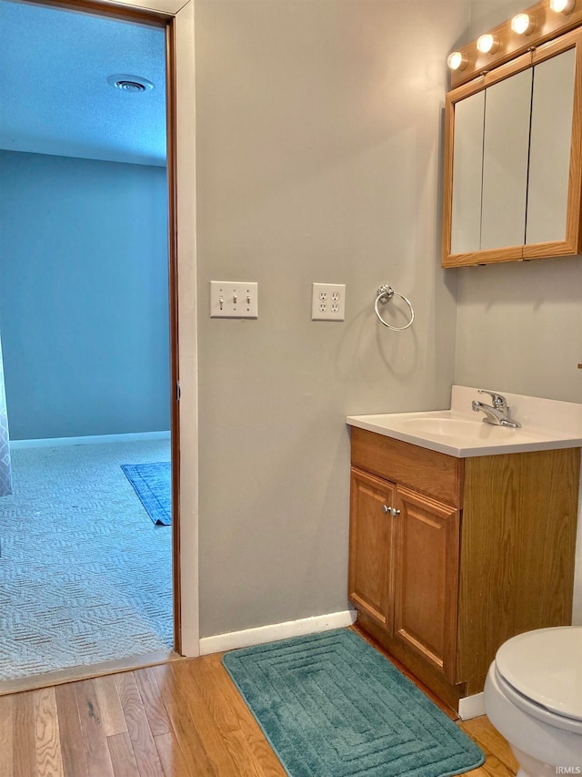 bathroom with vanity, toilet, a textured ceiling, and hardwood / wood-style floors