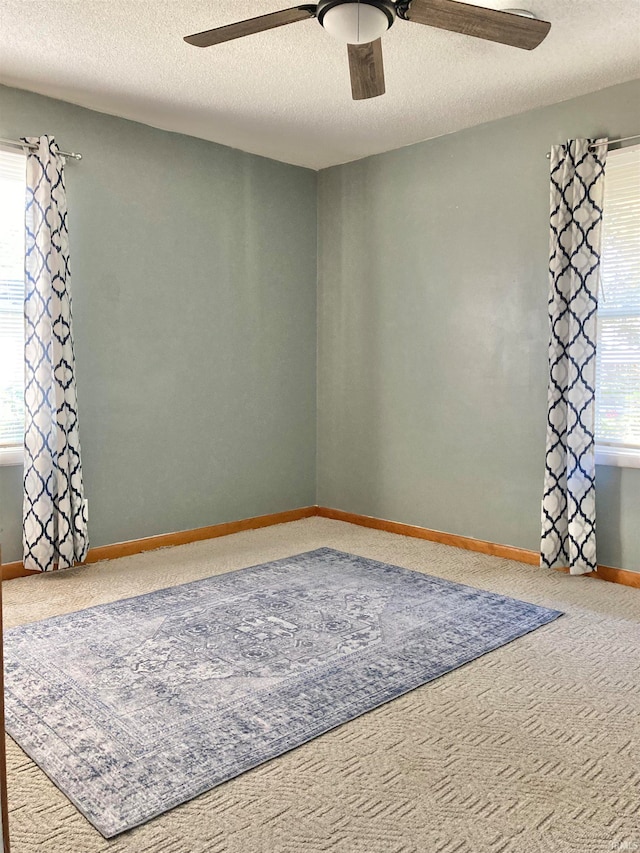 carpeted spare room with a textured ceiling and ceiling fan