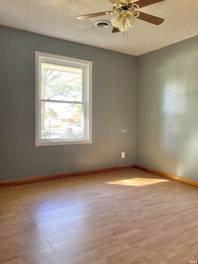 spare room featuring a textured ceiling, light wood-type flooring, and ceiling fan