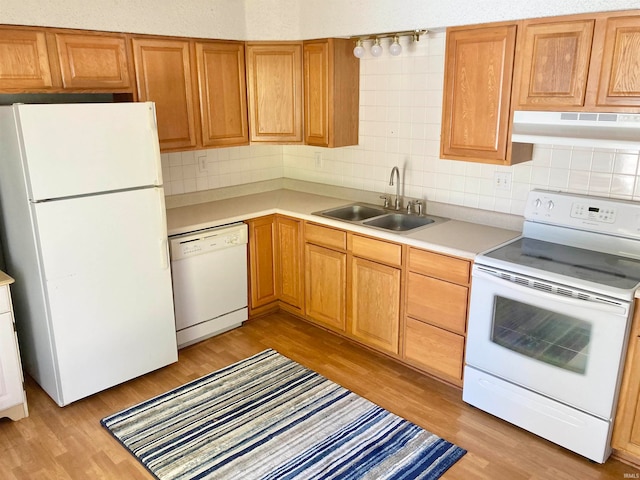 kitchen with decorative backsplash, white appliances, range hood, sink, and light hardwood / wood-style floors