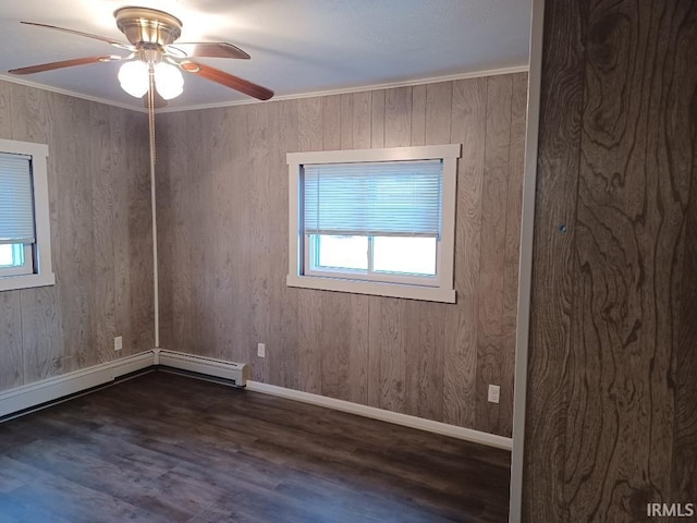 spare room featuring ornamental molding, ceiling fan, wooden walls, a baseboard radiator, and dark hardwood / wood-style floors