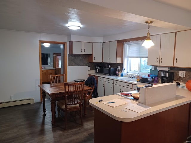 kitchen featuring sink, dark wood-type flooring, kitchen peninsula, decorative light fixtures, and white cabinets