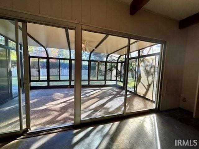 entryway with beamed ceiling and concrete flooring